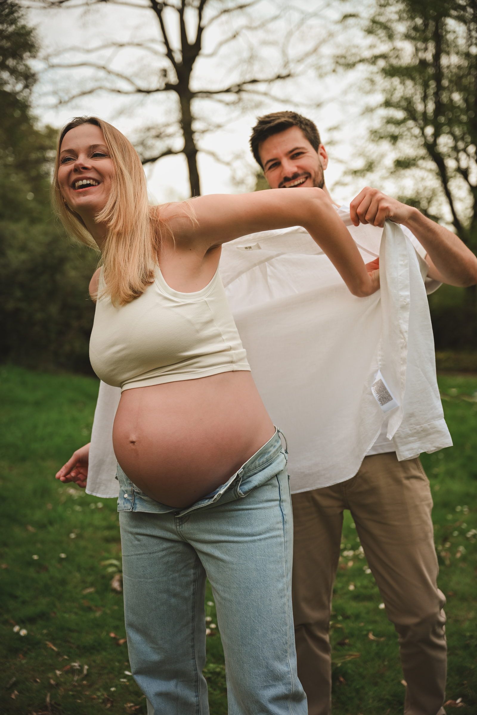 Futurs parents qui jouent avec une chemise dans un parc, éclats de rire