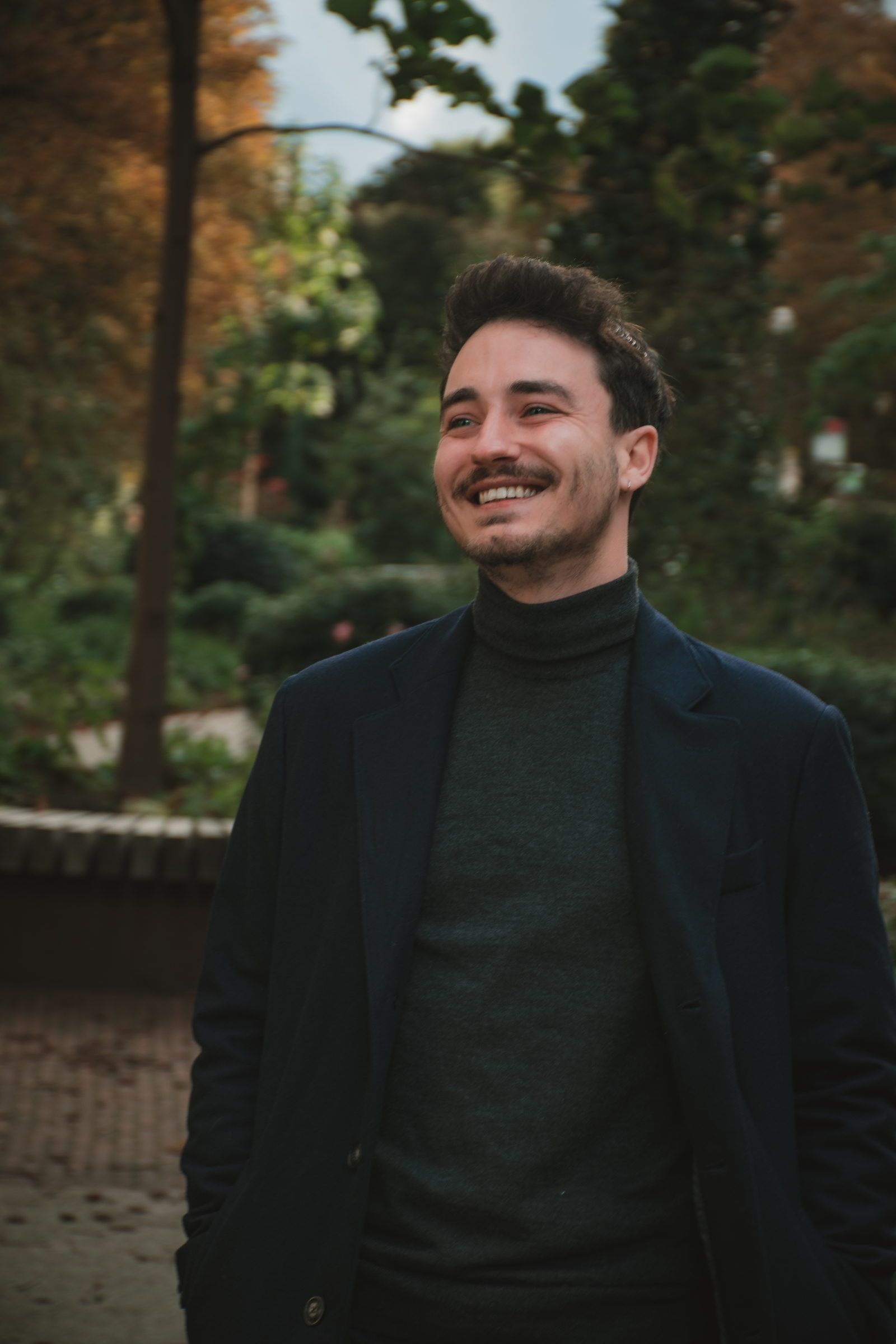 Homme en manteau qui rit dans un parc en automne